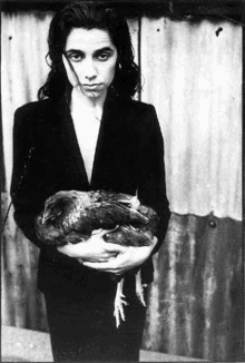 a black and white photo of a woman holding a chicken in her hands .