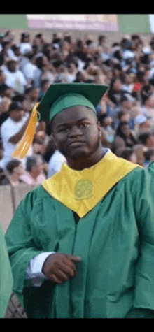 a man in a graduation cap and gown is pointing at the camera