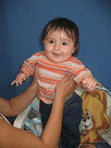 a baby is being held up by a woman in front of a blue wall