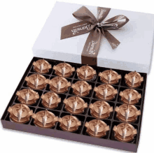 a box of chocolates with a brown ribbon and a bow on it .