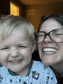 a woman wearing glasses smiles next to a baby