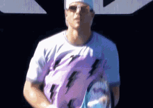 a man wearing a purple shirt with lightning bolts on it holds a tennis racquet