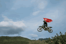 a person riding a dirt bike with a red flag flying over their head