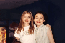 two young girls pose for a picture in front of a pepsi fridge