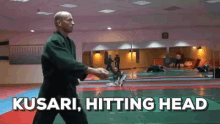 a man in a karate uniform is standing on a mat with the words " kusari hitting head " above him