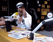 a man sitting at a desk with a microphone and a sign that says ' radio station ' on it