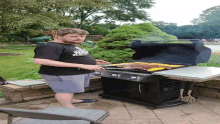 a man cooking on a grill with a shirt that says ' texas tech ' on the front of it