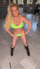 a woman in a neon green bikini is standing on a tile floor