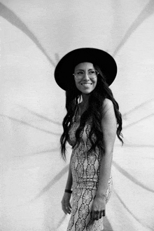 a woman wearing a black hat and glasses is smiling in a black and white photo