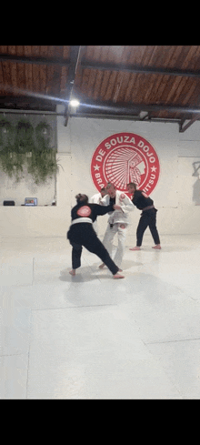 a group of people are practicing martial arts in front of a sign that says ' club de souza dojo '