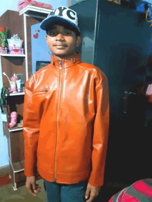 a boy wearing an orange fila jacket stands in front of a closet