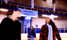 a man and a woman are walking on an ice rink .