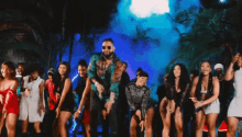 a group of people are dancing on a stage in front of palm trees .