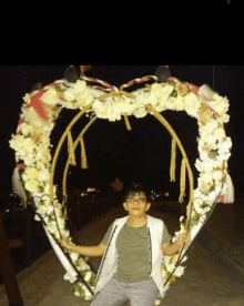 a young man stands in front of a heart shaped decoration