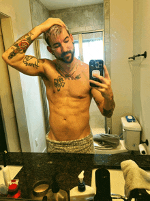 a shirtless man taking a picture of himself in a bathroom mirror with a tattoo on his arm that says bartlett