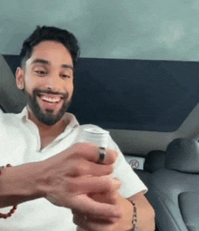 a man is sitting in the back seat of a car holding a can of soda .