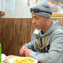 a man sitting at a table with a plate of french fries and a name tag that says ' a ' on it