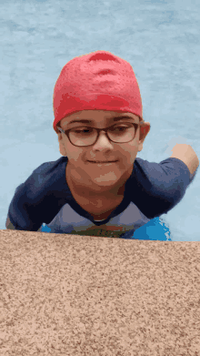 a young boy wearing glasses and a red swim cap is in a swimming pool