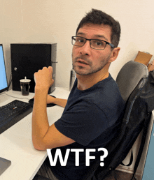 a man wearing glasses sits at a desk with the words wtf written on the bottom