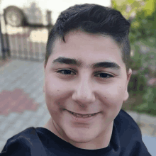 a young man with a black shirt on smiles for the camera