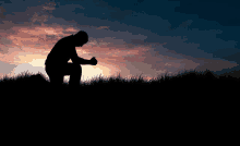 a silhouette of a man kneeling down with his hands folded