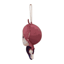 a stuffed toy with a red head is hanging from a gold chain