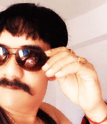 a man with a mustache wearing sunglasses and a ring