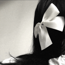 a black and white photo of a woman with a white bow in her hair