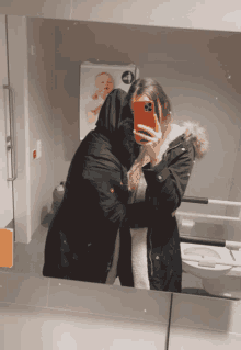 a woman taking a picture of herself and another woman in a bathroom mirror