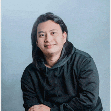 a young man with long hair wearing a black hoodie