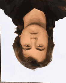 a man 's head is upside down and looking at the camera