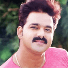 a close up of a man with a mustache wearing a pink shirt and smiling .