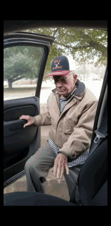 a man wearing a hat that says ' army ' on it sits in the back seat of a car