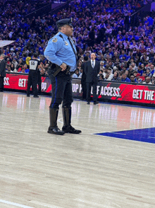 a police officer stands on a basketball court in front of a sign that says " get the access "