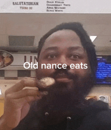 a man with a beard is eating a donut and the words old nance eats are above him