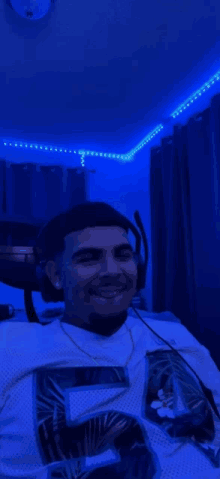 a man wearing headphones and a jersey with the number 5 on it is sitting in a room with blue lights .