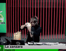 a man is eating a hamburger in front of a microphone at radio 24