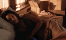 a woman is laying in a bed with boxes behind her