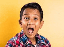 a young boy in a plaid shirt is making a surprised face .