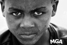 a black and white photo of a young boy 's face with a serious look on his face .