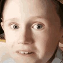 a close up of a young boy 's face with a funny look on his face .