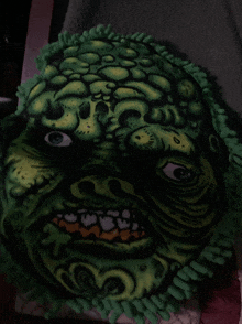 a blanket with a green monster face on it is sitting on a bed