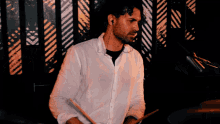 a man in a white shirt plays drums in front of a striped wall