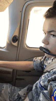 a young boy in a military uniform is wearing a headset and a patch that says air force