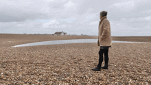 a woman standing on a beach with a house in the distance