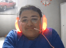 a man wearing headphones and glasses looks at the camera with a clock on the wall behind him