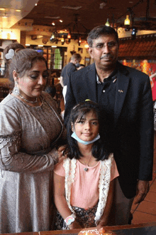 a family posing for a picture with a little girl wearing a mask