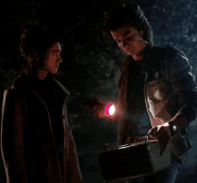 a man is holding a flashlight next to a woman who is holding a toolbox