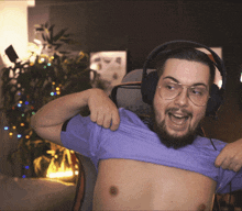 a shirtless man wearing headphones and glasses is taking off his shirt