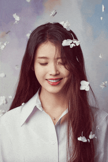 a woman with flowers in her hair is smiling and wearing a white shirt